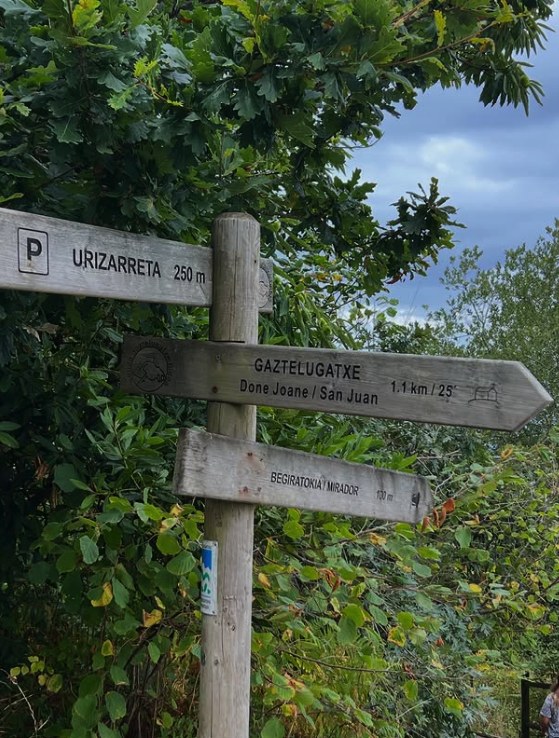 Wooden waymarker signing Gaztelugatxe Done Joane at 1.1 km and 25 minutes