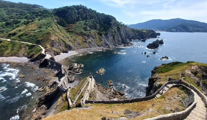 San Juan de Gaztelugatxe under a bright sky with the staircase visible along the ridge