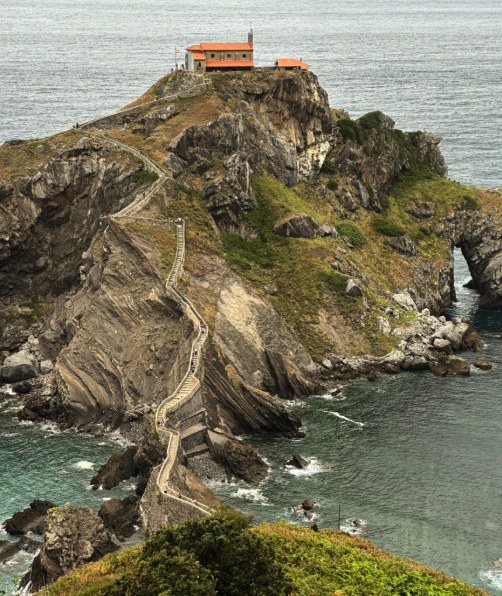 The zig-zag stone staircase climbing San Juan de Gaztelugatxe with walkers on the steps